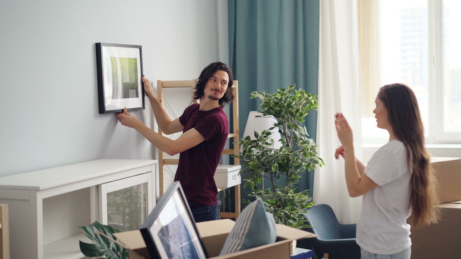 A couple settling into their new home, hanging art after a Great Wall move